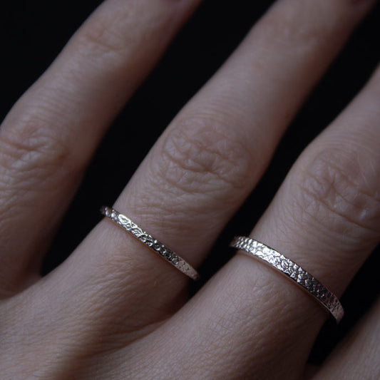 Close-up of a hand wearing two silver rings on a dark background