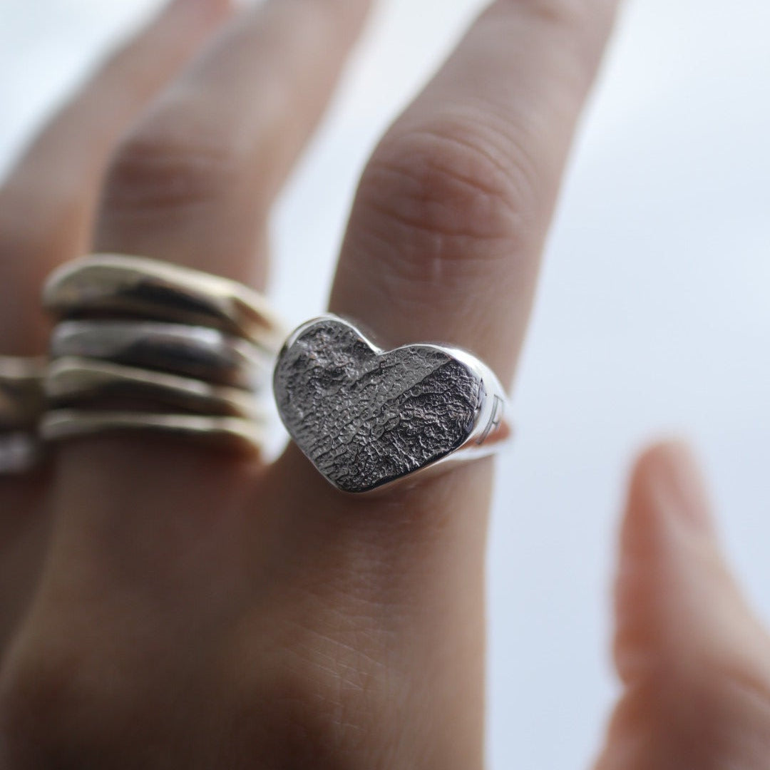 Hand wearing a textured silver ring on a blurred background